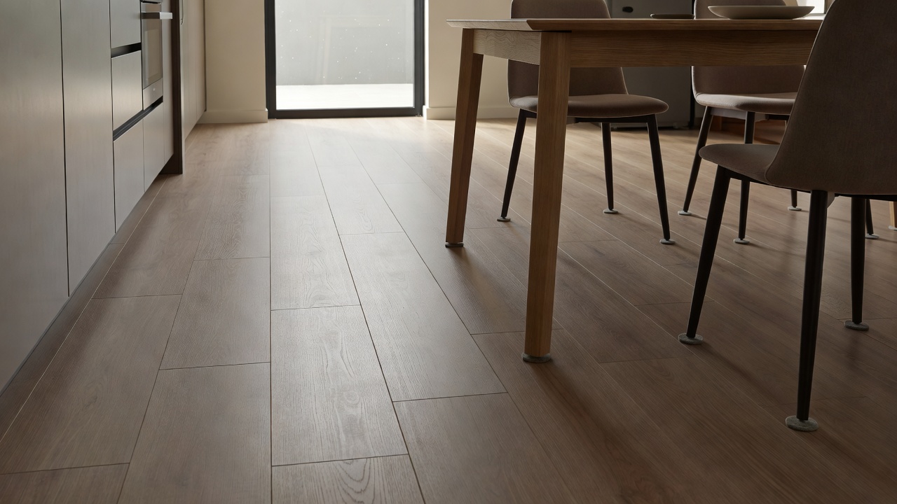 photorealistic kitchen scene with matte AC3 laminate planks under a table, felt pads on chair legs, subtle traffic path toward a patio door, natural side light 